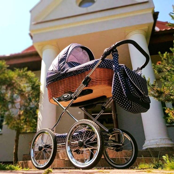 Elegancki wózek dziecięcy z wiklinową gondolą, ustawiony przed budynkiem.